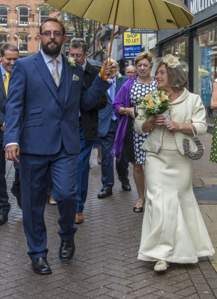 Wool bridal wear: Image of bride and husband walking to wedding reception. The bride wears Shetland wool suit (jacket and long skirt with handknit Ryeland wool top)