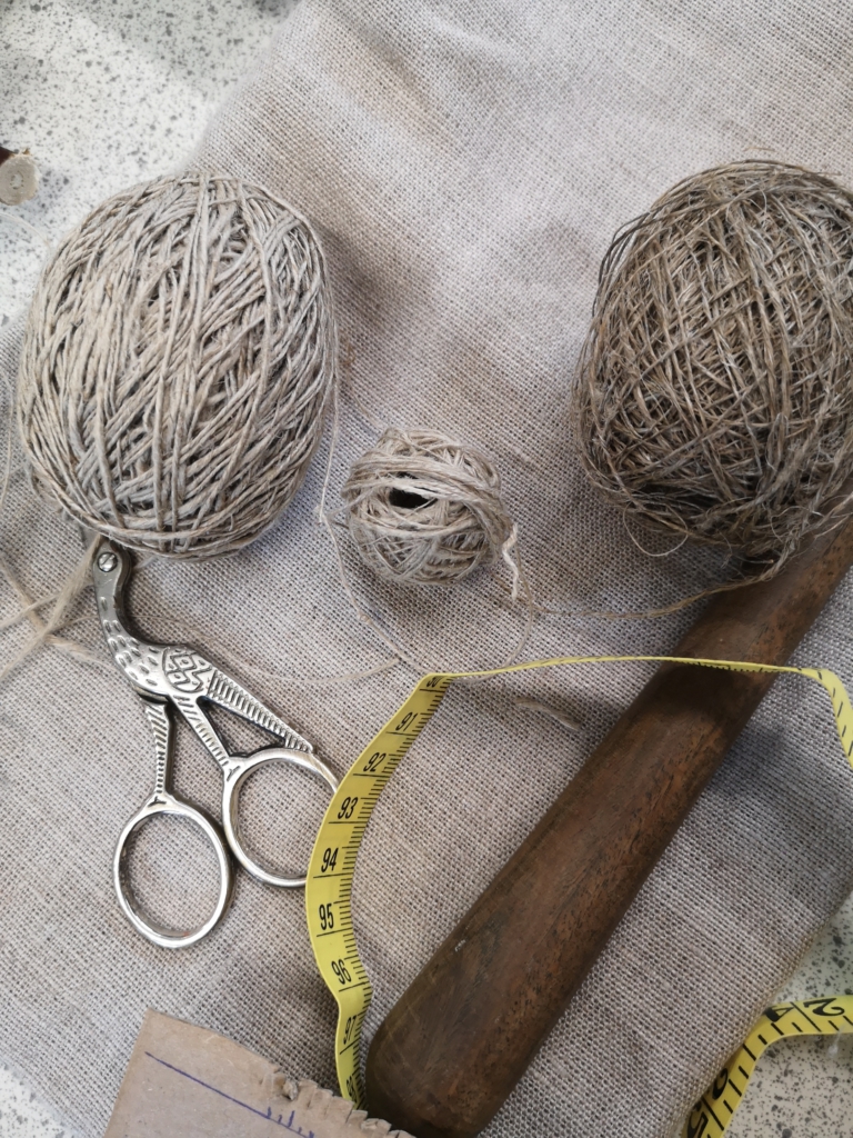 Ancestral living with flax yarn: image of fine, handspun flax yarn, scissors and measuring tape.